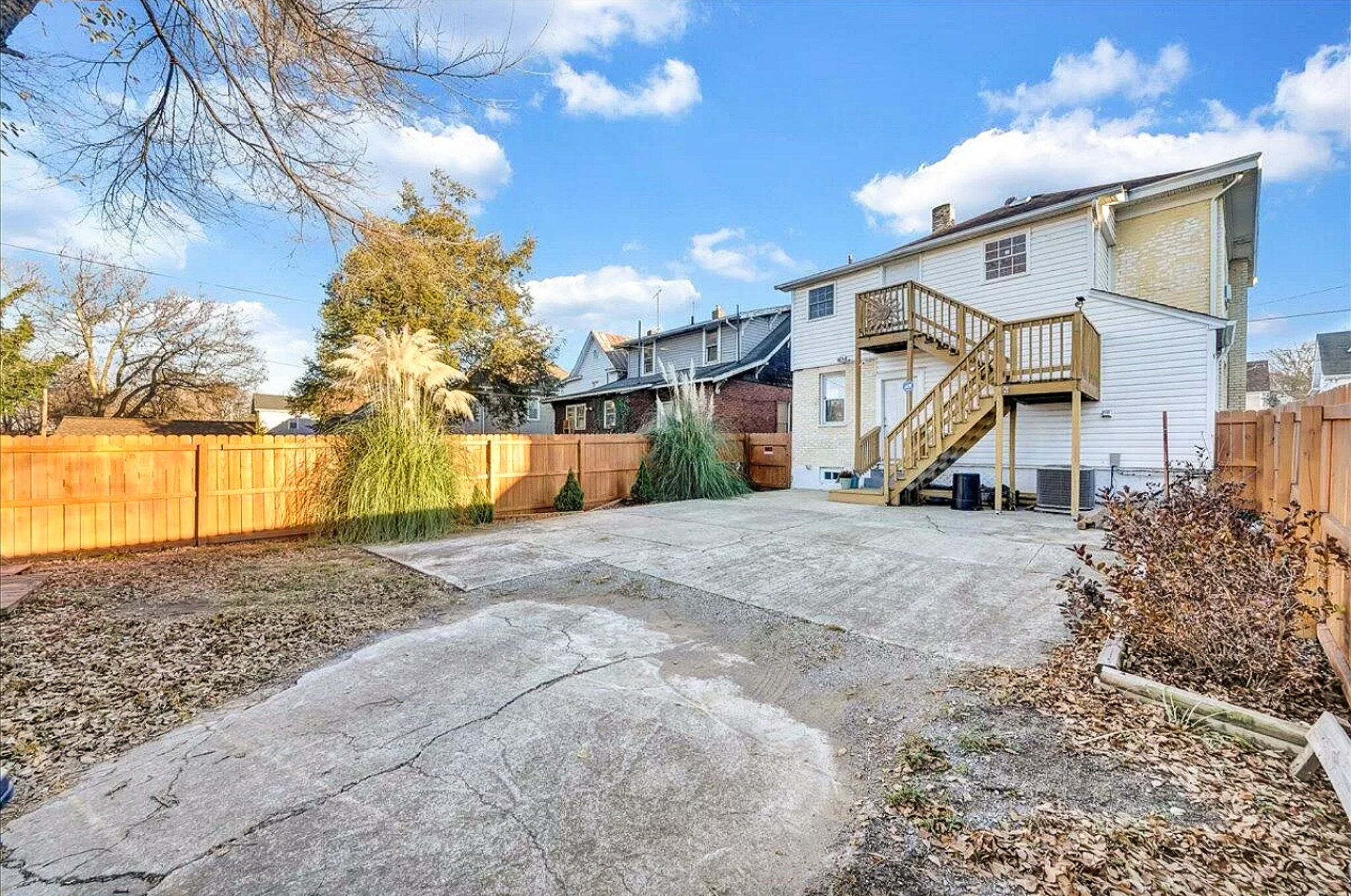 A backyard with a large paved area, a fenced perimeter, and a house with an exterior staircase leading to an upper entrance belonging to Sponsored Residential Provider Jessica Peregrino in Roanoke, Virginia.