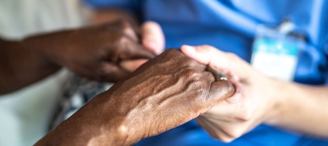 Close up of a nurse holding a patient's hands