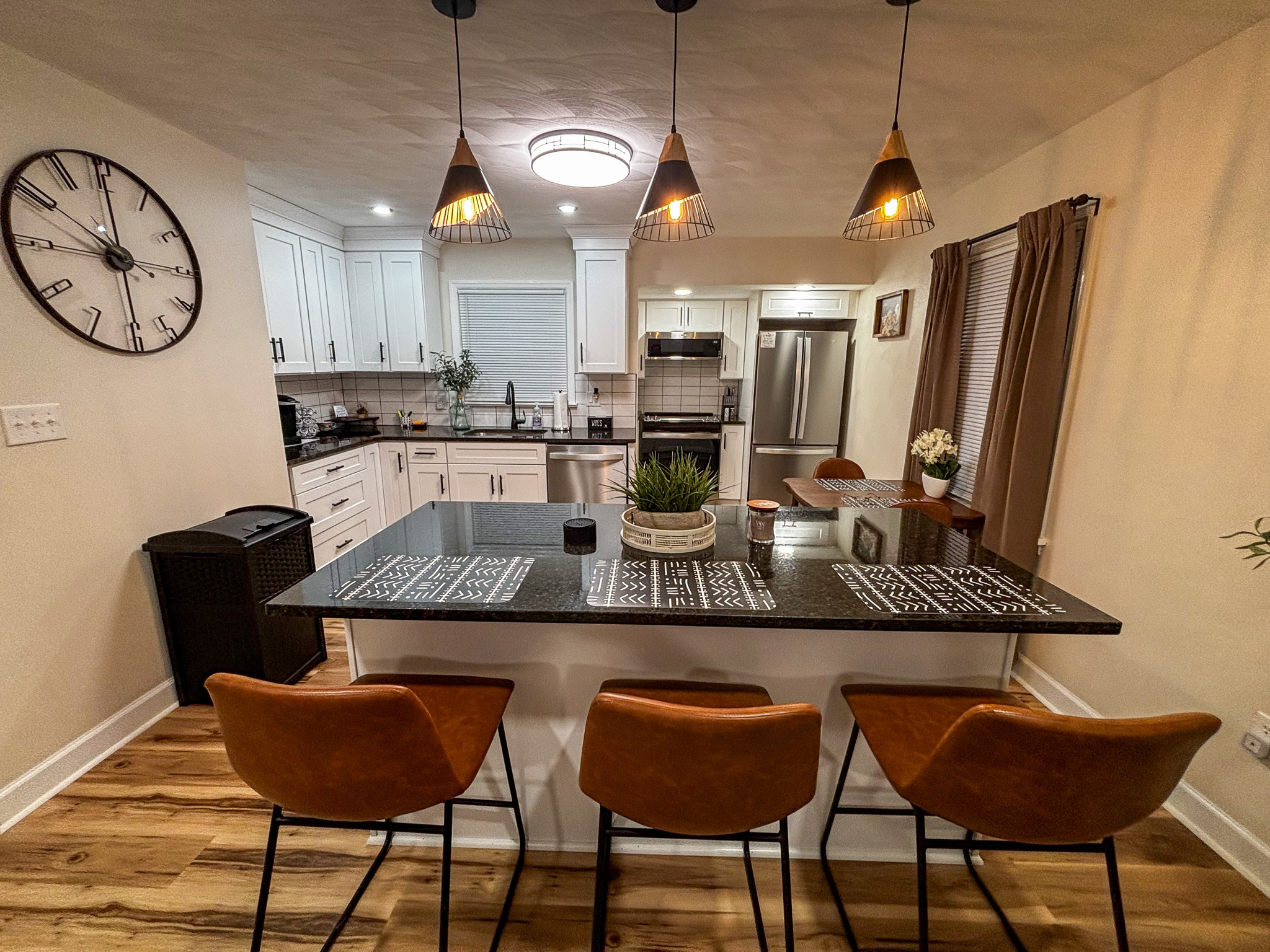 A modern kitchen with a large island, three bar stools, and pendant lights inside the home of sponsored residential provider Regina Hill in Roanoke, Virginia.