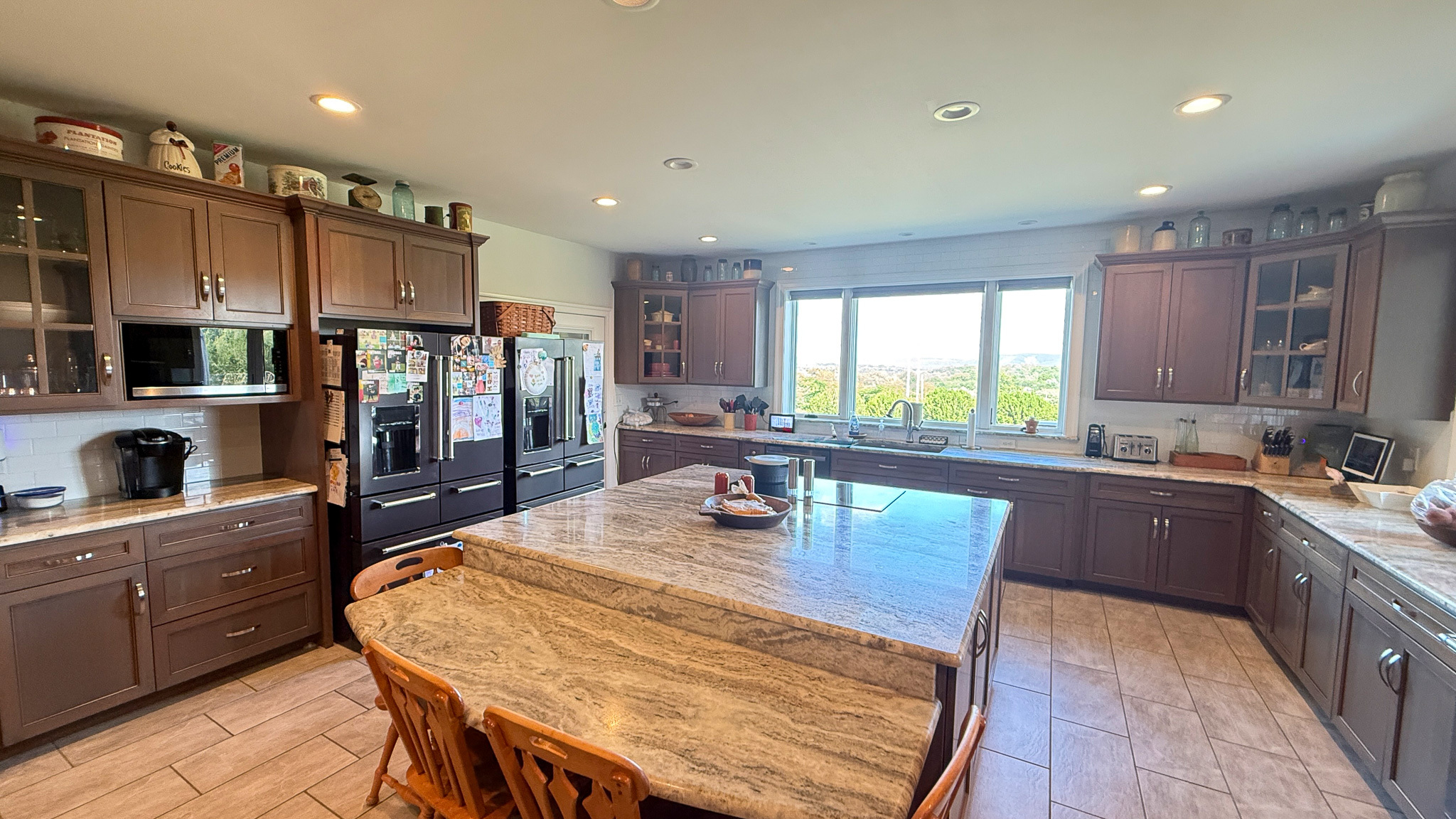 Kitchen with island, dark cabinets, and a large window overlooking a landscape  inside the home of Group home providers Rhonda and Bruce Norconk in Lynchburg, VA.