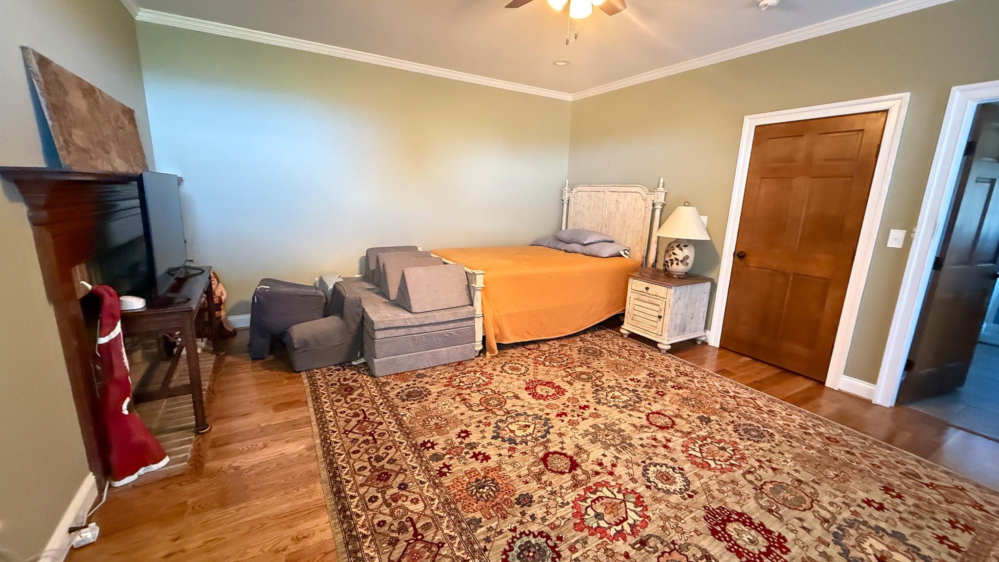 Bedroom with a bed, patterned rug, and a dresser with a TV inside the home of Group home providers Rhonda and Bruce Norconk in Lynchburg, VA.