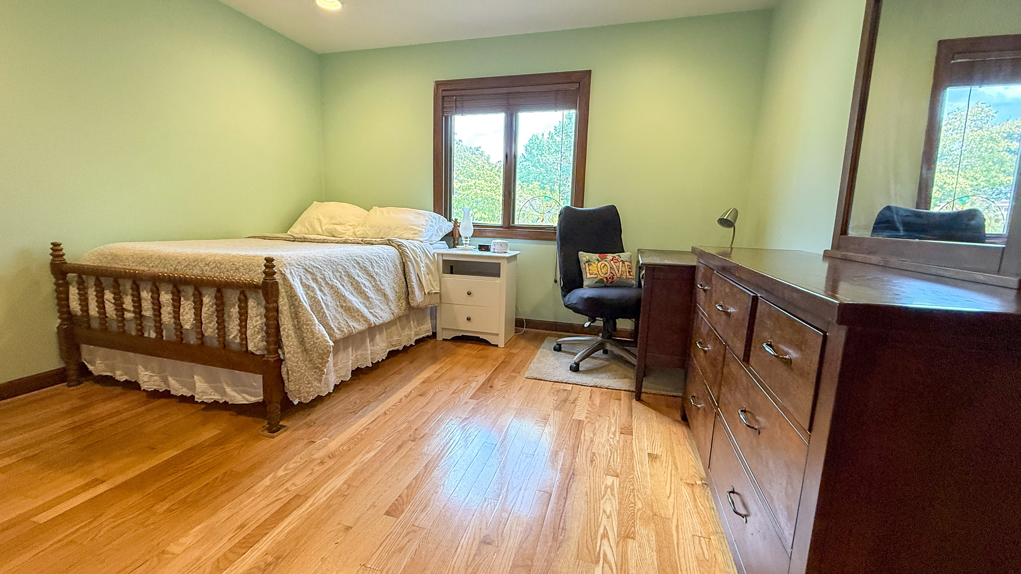 Spacious bedroom with hardwood floors, a workspace, and large windows inside the home of Sponsored Residential Providers Anna Robertson and Christopher Pietrzyk in Roanoke, VA.