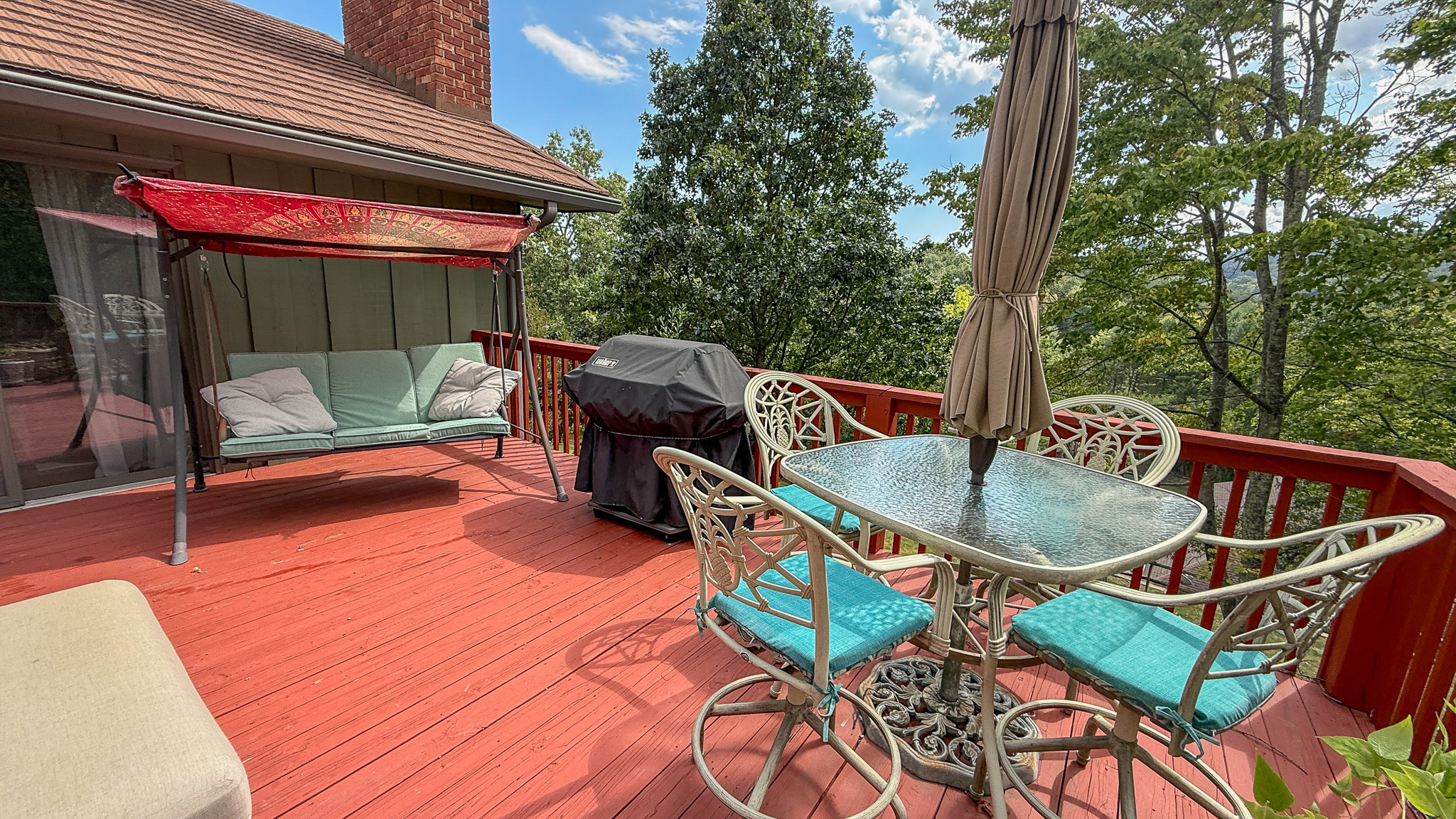Outdoor deck with seating, dining space, and wooded views inside the home of Sponsored Residential Providers Anna Robertson and Christopher Pietrzyk in Roanoke, VA.