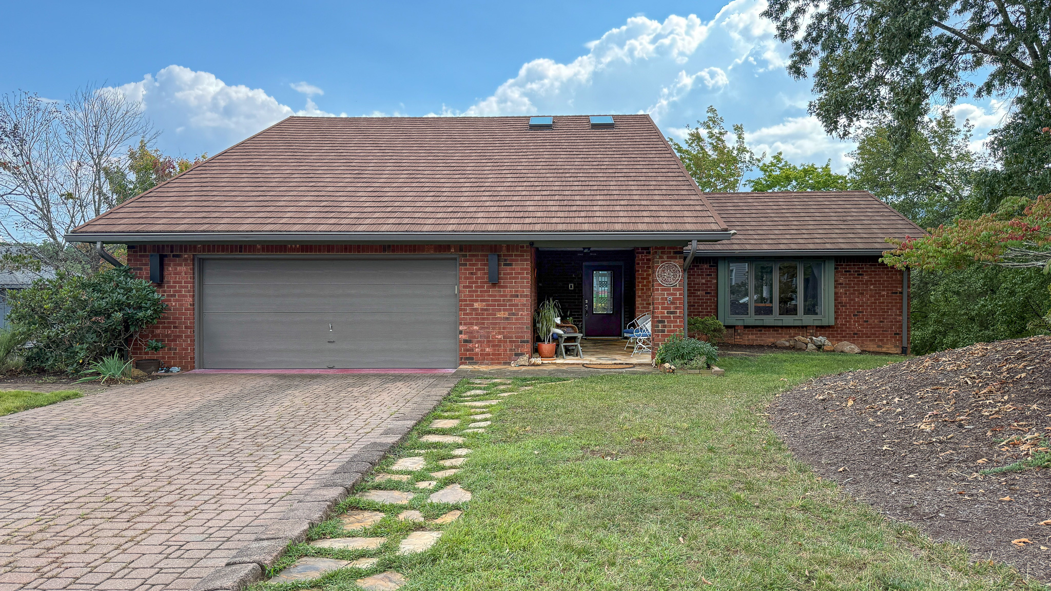 Exterior view of the home of Sponsored Residential Providers Anna Robertson and Christopher Pietrzyk in Roanoke, VA, featuring a brick façade, attached two-car garage, and landscaped front yard.
