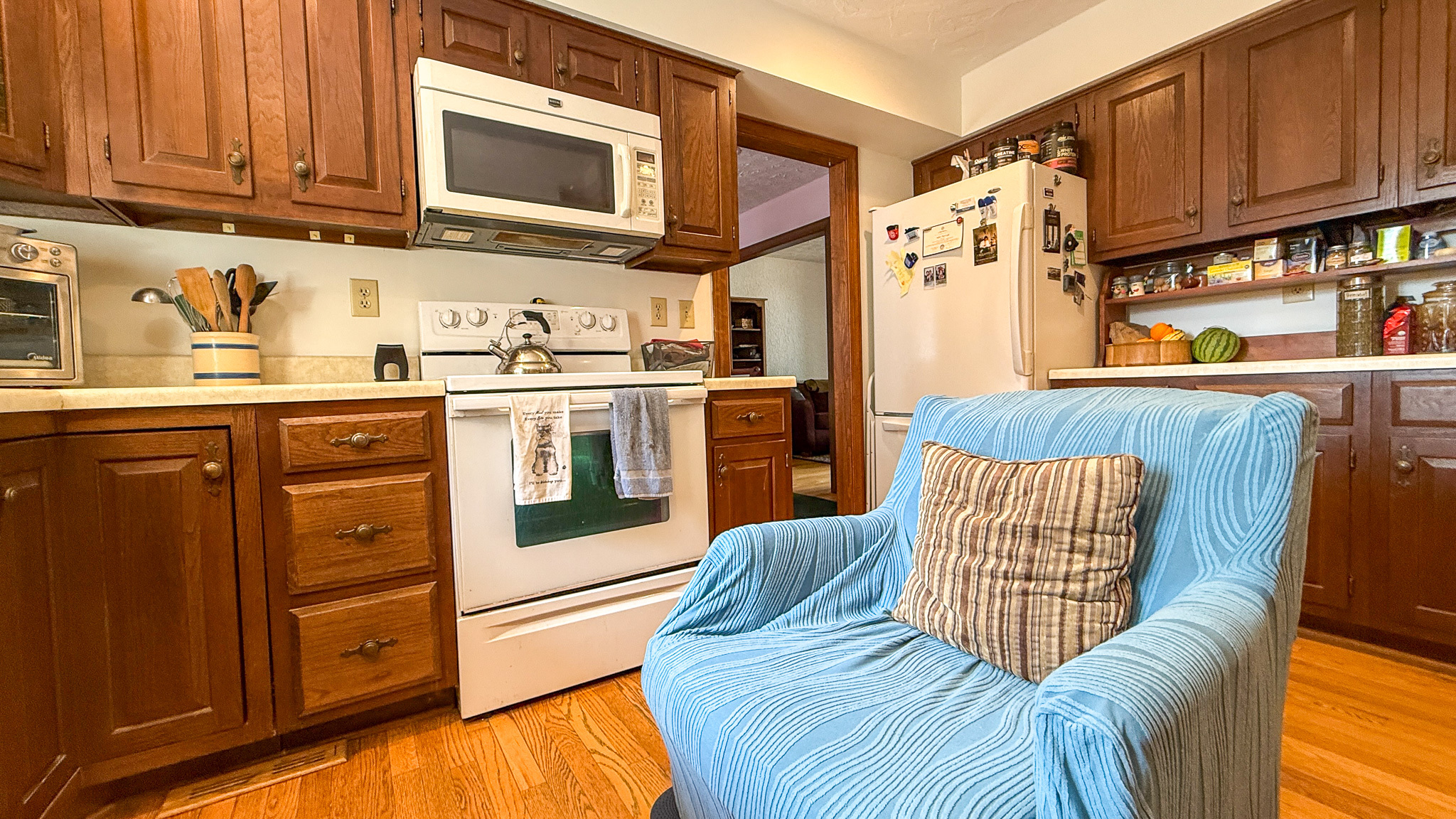 Cozy kitchen with wood cabinetry, hardwood floors, and a seating area inside the home of Sponsored Residential Providers Anna Robertson and Christopher Pietrzyk in Roanoke, VA.