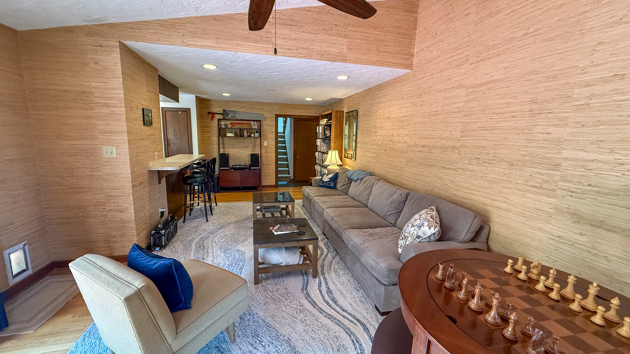 Comfortable sitting area with a sectional sofa, chess table, and bar seating inside the home of Sponsored Residential Providers Anna Robertson and Christopher Pietrzyk in Roanoke, VA.