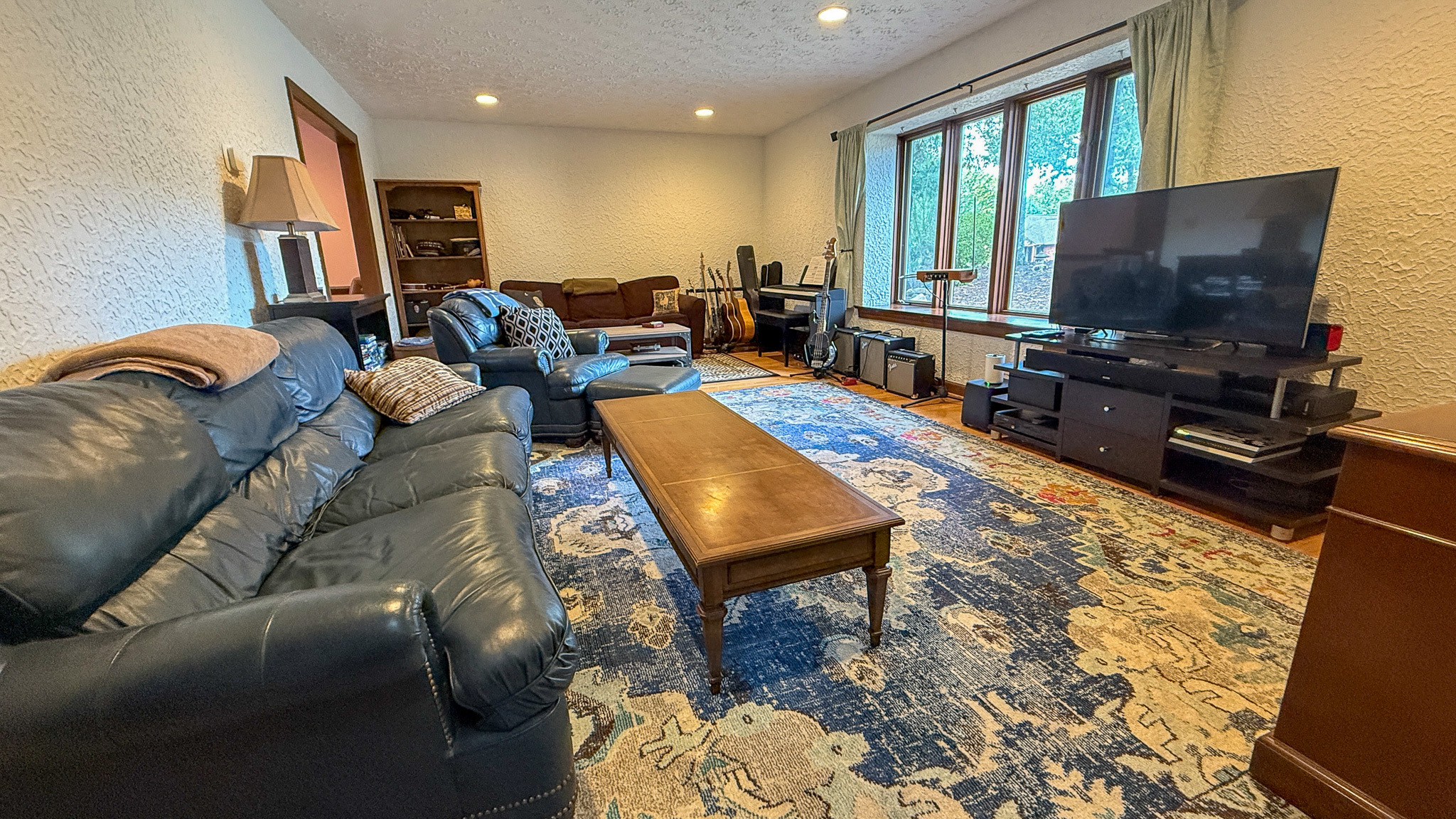 Bright living room featuring sofas, a large television, and natural light from oversized windows inside the home of Sponsored Residential Providers Anna Robertson and Christopher Pietrzyk in Roanoke, VA.