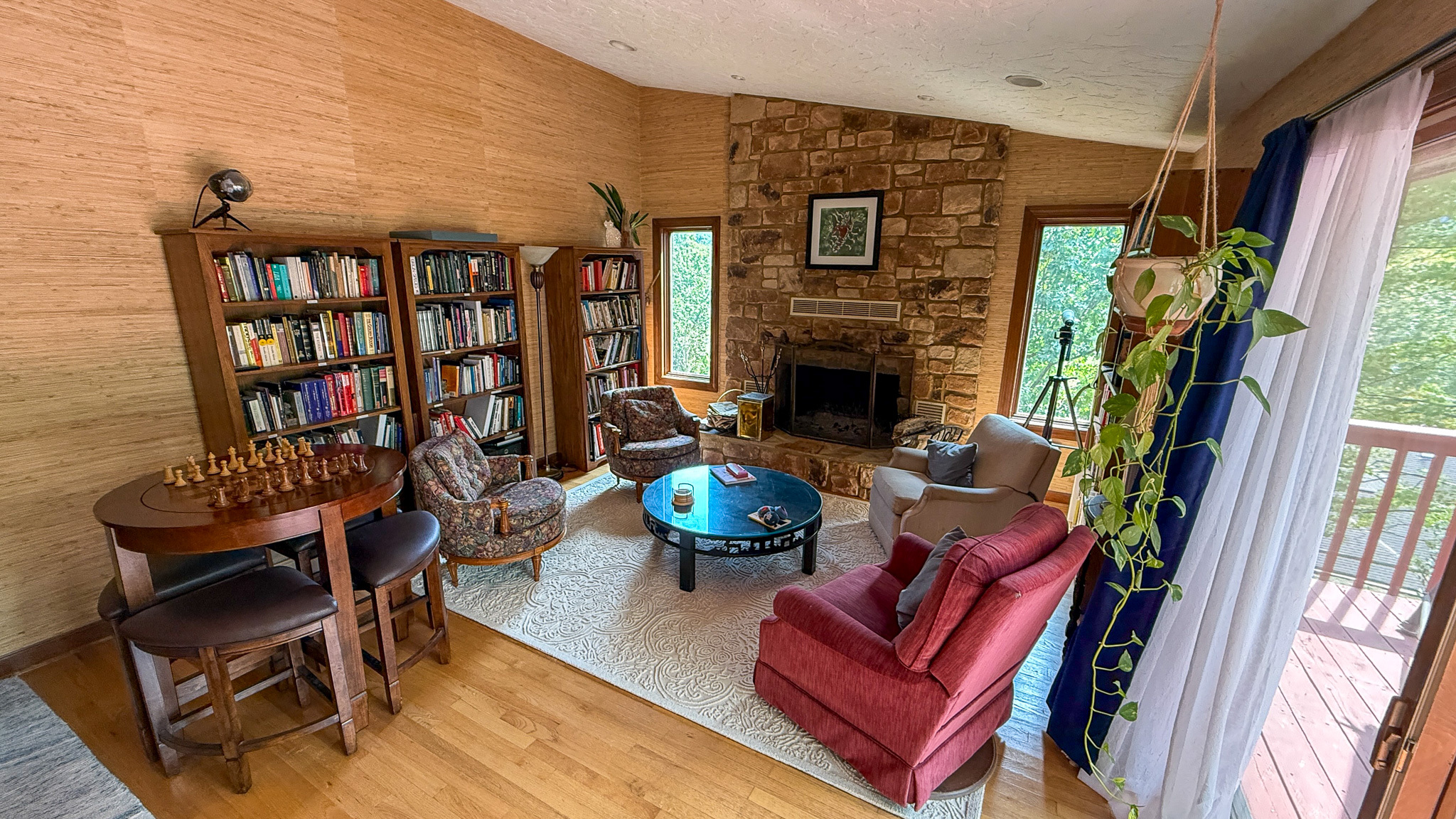 Cozy sitting room with a stone fireplace, bookshelves, and a chess table inside the home of Sponsored Residential Providers Anna Robertson and Christopher Pietrzyk in Roanoke, VA.
