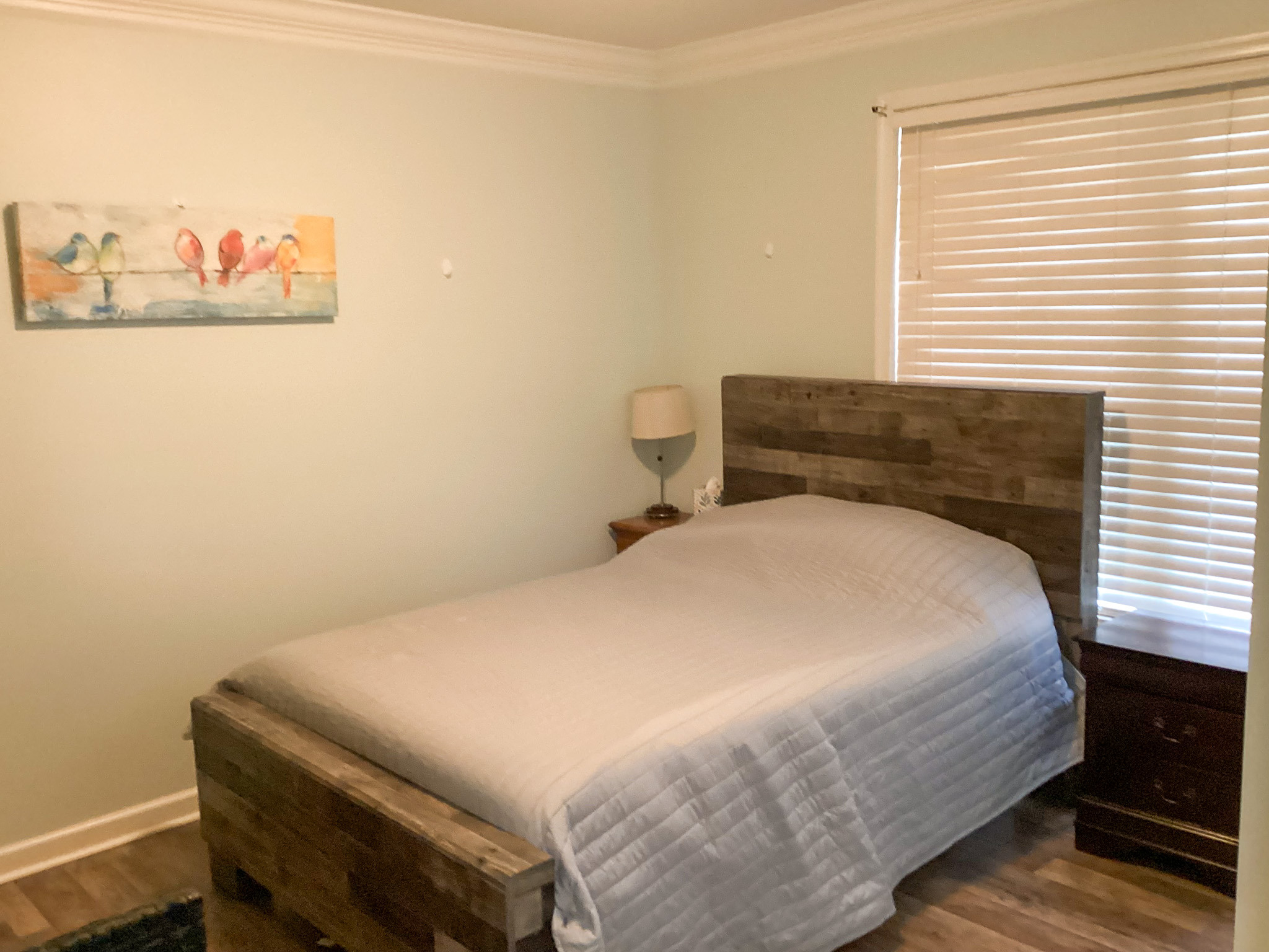 Inviting bedroom with a wood bed frame, soft bedding, and warm decor in the home of Sponsored Residential Provider Roxane Barnes.