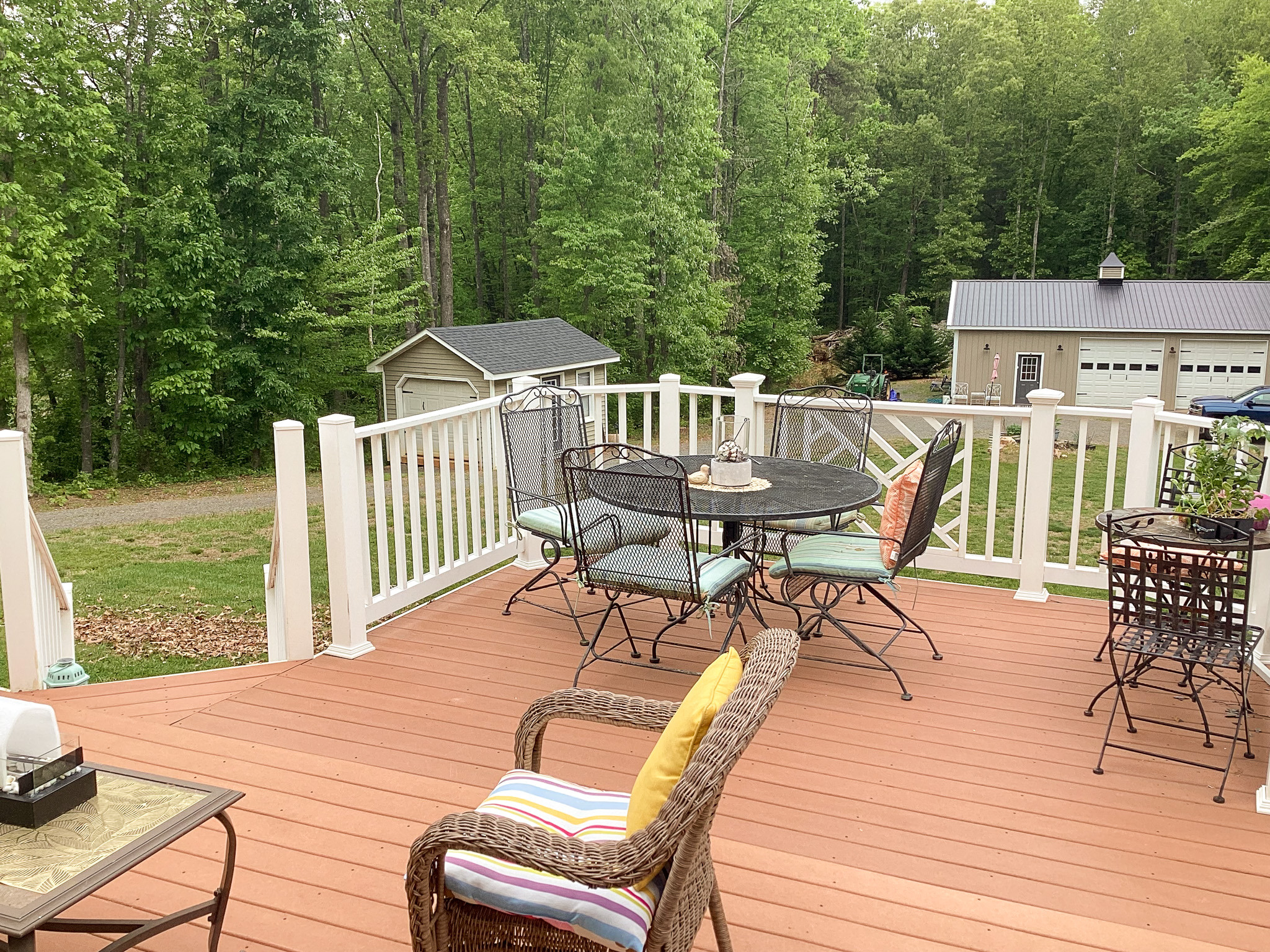 Welcoming deck with cushioned seating, dining table, and peaceful wooded views at the home of Sponsored Residential Provider Roxane Barnes.
