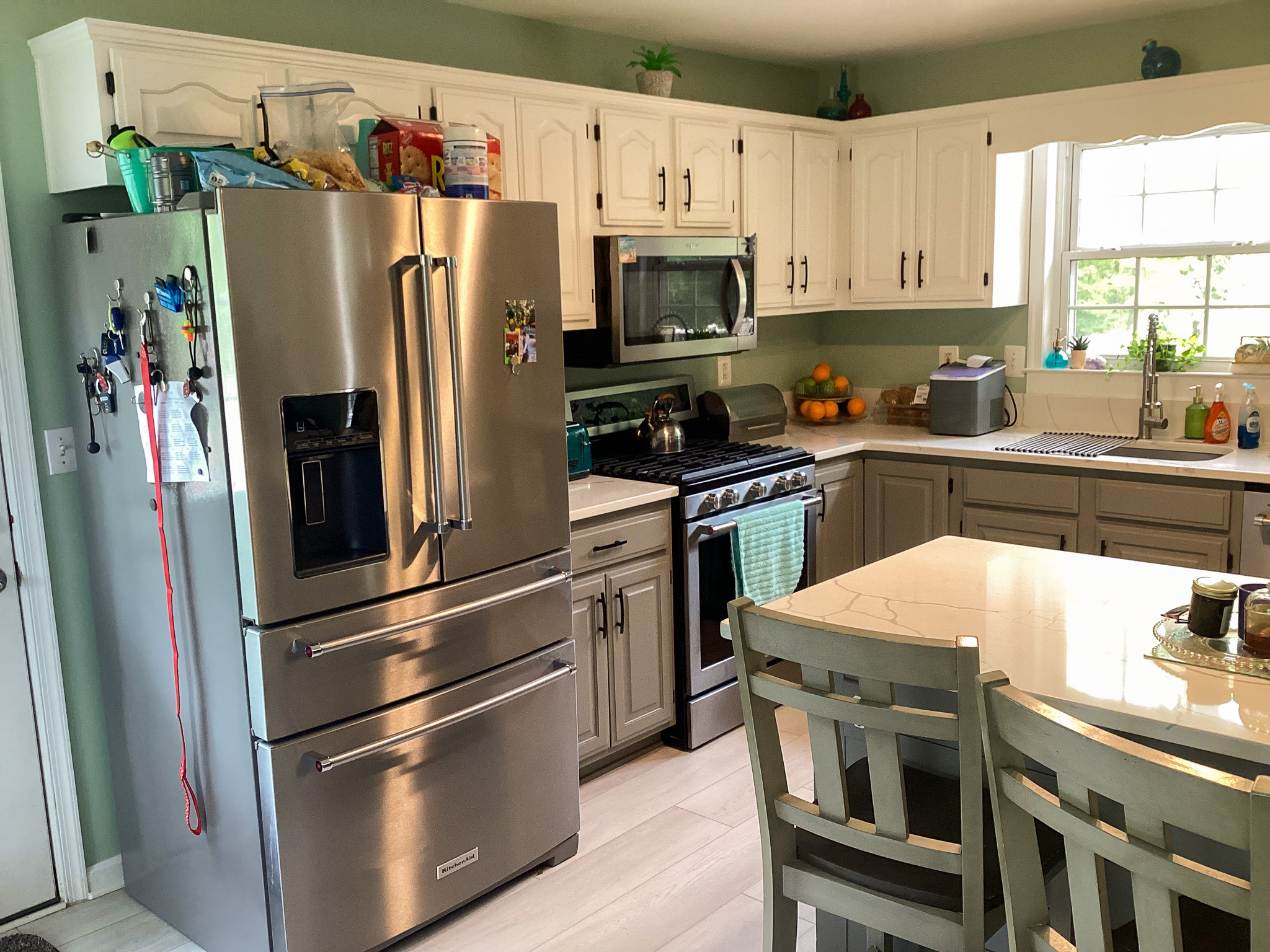 Bright, welcoming kitchen with stainless steel appliances, white cabinets, and a cozy dining island, in the home of Sponsored Residential Provider Roxane Barnes.