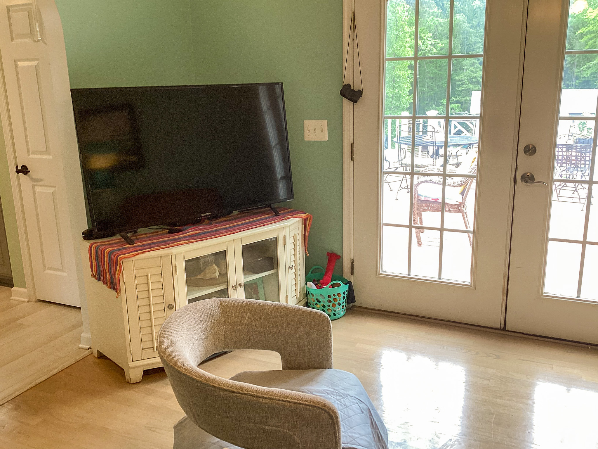 Comfortable living space with a TV on a stand, soft seating, and bright doors leading outside in the home of Sponsored Residential Provider Roxane Barnes.