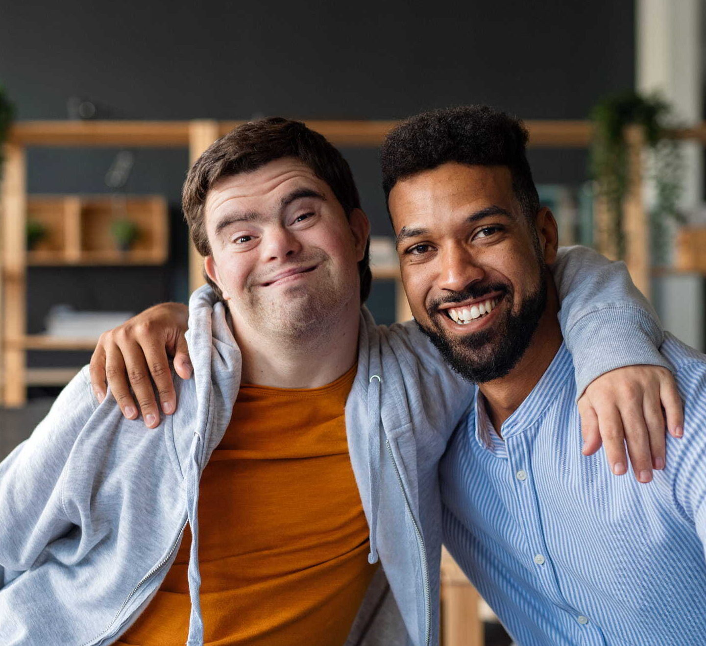 Two men sitting on a couch and smiling into the camera