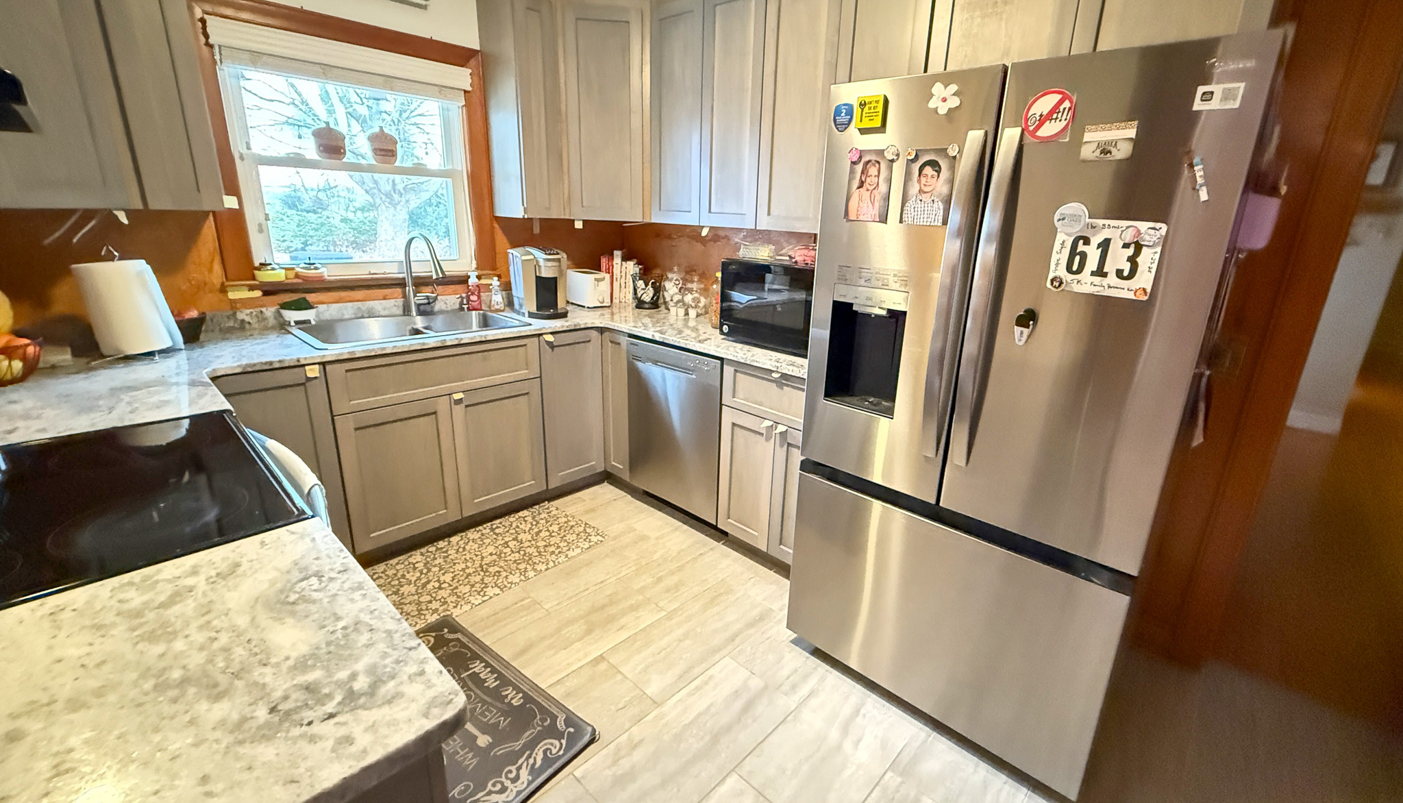 A kitchen with gray cabinets, stainless steel appliances, and a marble‑style countertop surrounding a corner sink inside the home of Sponsored Residential Providers Angela and James Snyder in Rocky Mount, Virginia.