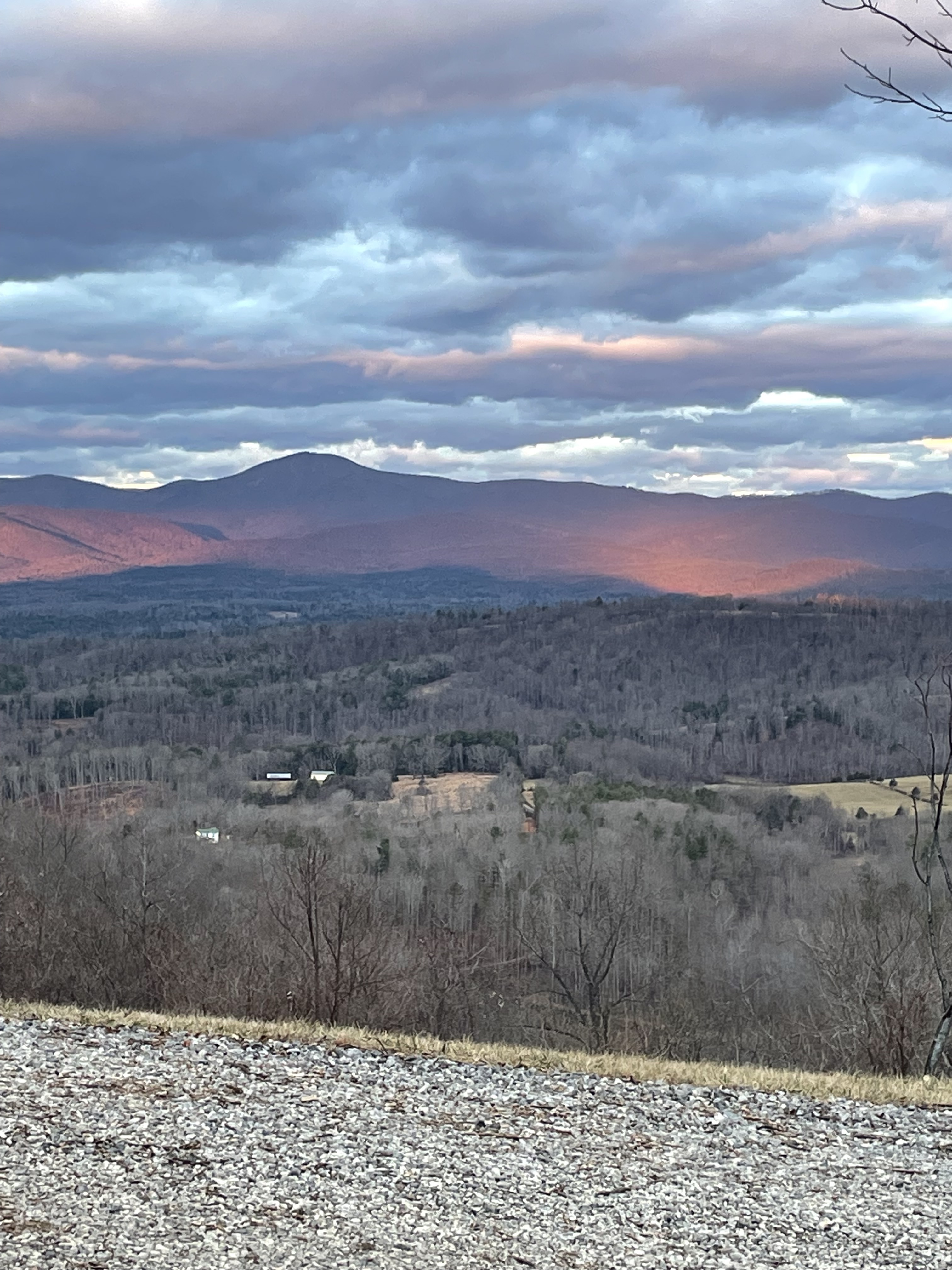 Mountain landscape with rolling hills, a cloudy sky, and soft sunset light casting a warm glow on distant slope at the home of Sponsored Residential Providers Jimmy and Nancy Ayers in Monroe, Virginia.