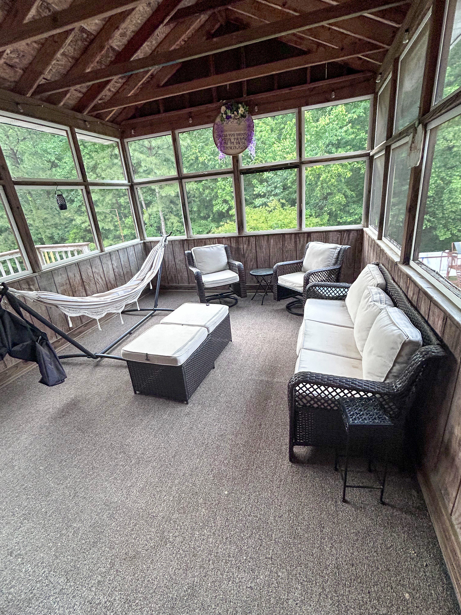 Large two-story brick home with green shutters, a centered screened front porch with white columns, and a curved driveway in a quiet, wooded setting belonging to Sponsored Residential Provider Wanette and Carol Spencer in Richmond, Virginia.