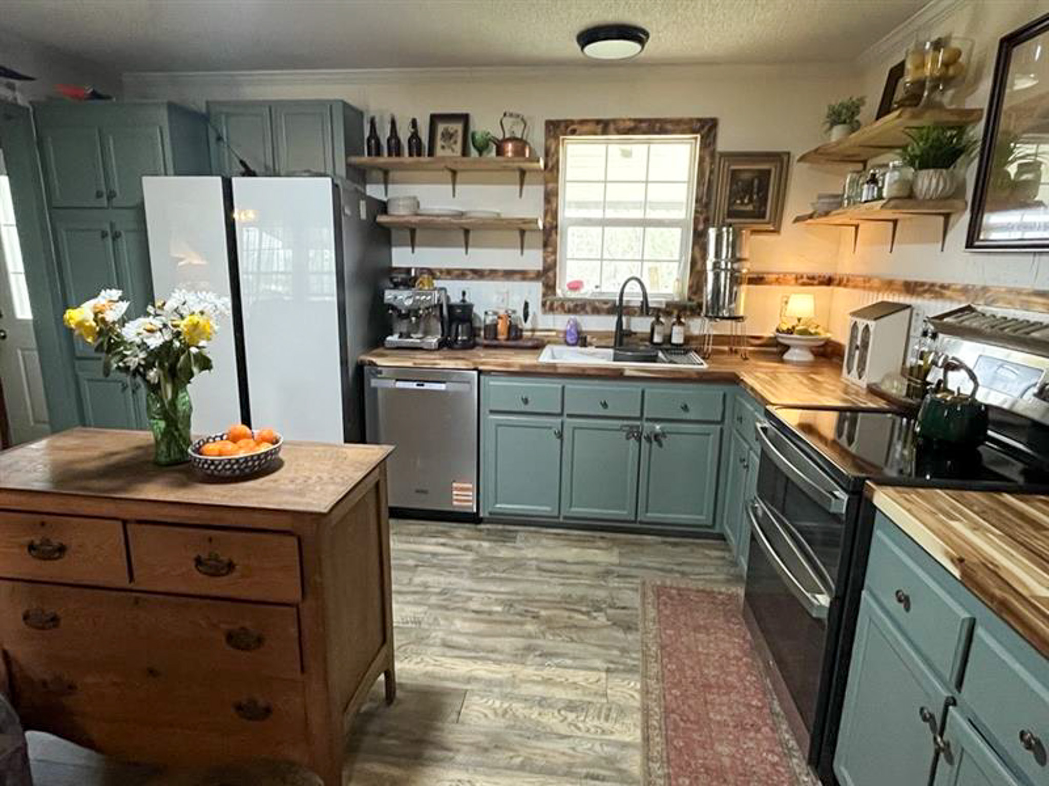 Kitchen with green cabinets, stainless appliances, wood countertops, and small island inside the home of Sponsored Residential Provider Kristen Bowers in Galax, Virginia.