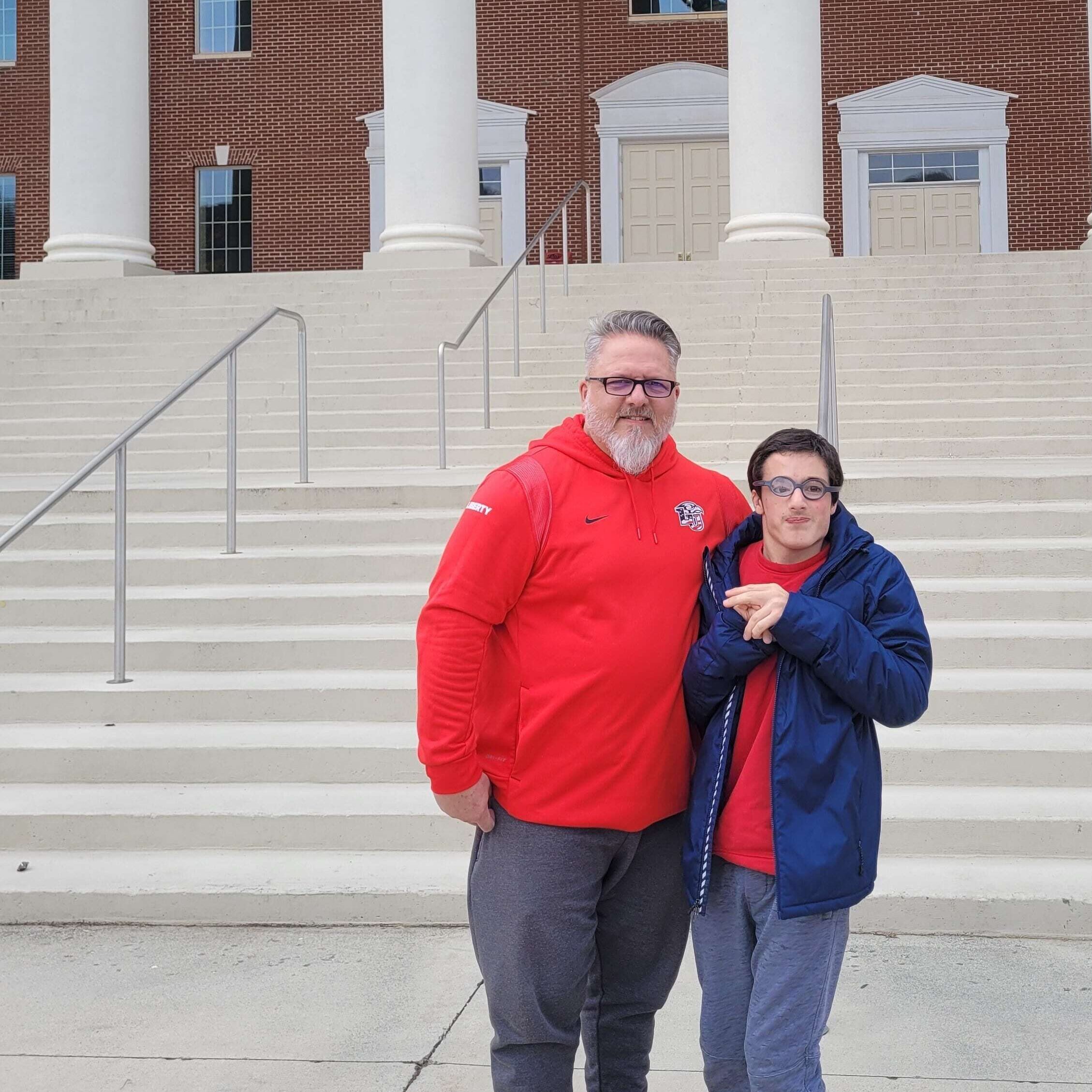 Two men posing in outside on their way to a college basketball game