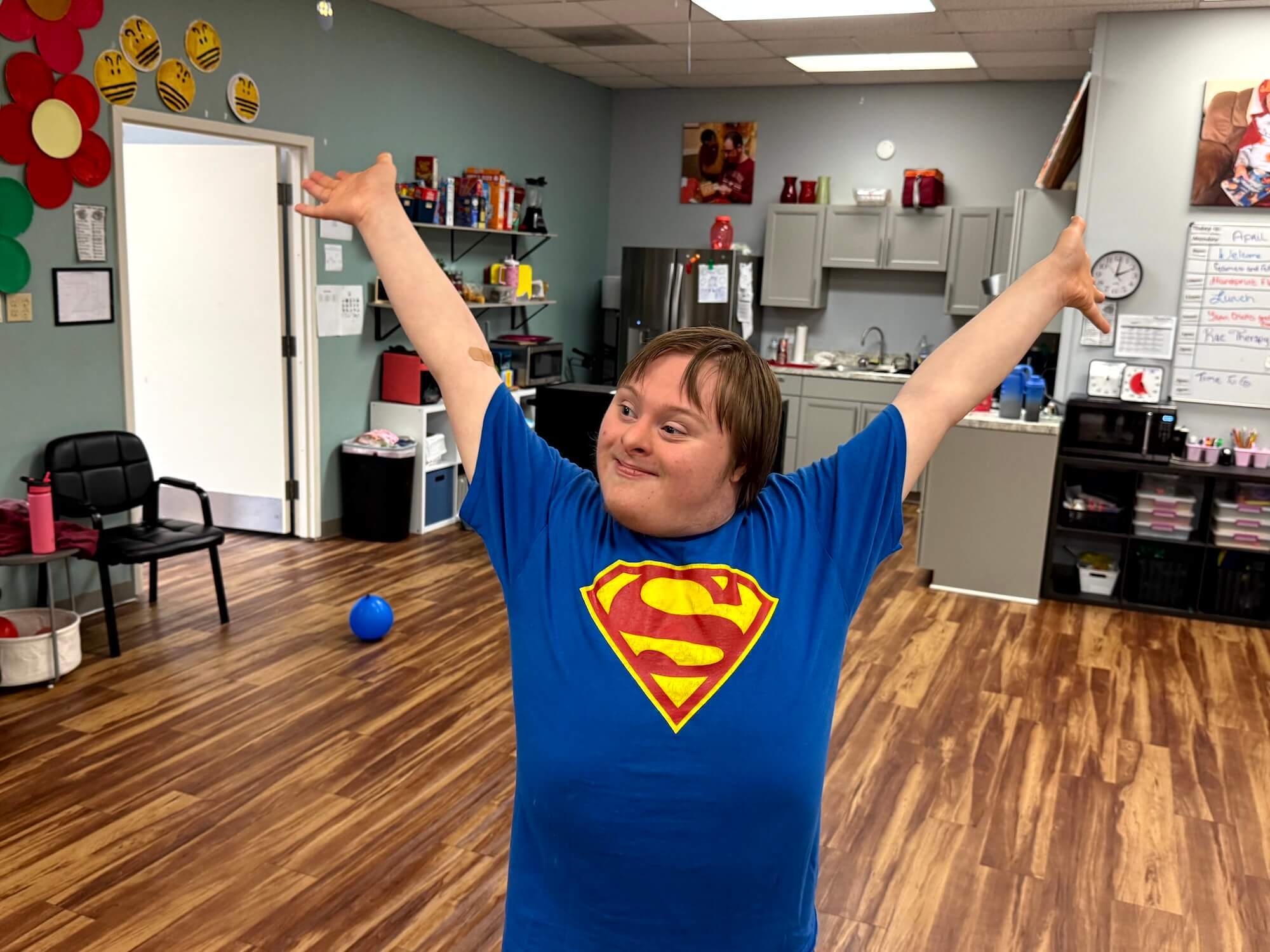 Boy in blue shirt with Superman logo with arms raised high and smiling inside Wall Star Center.