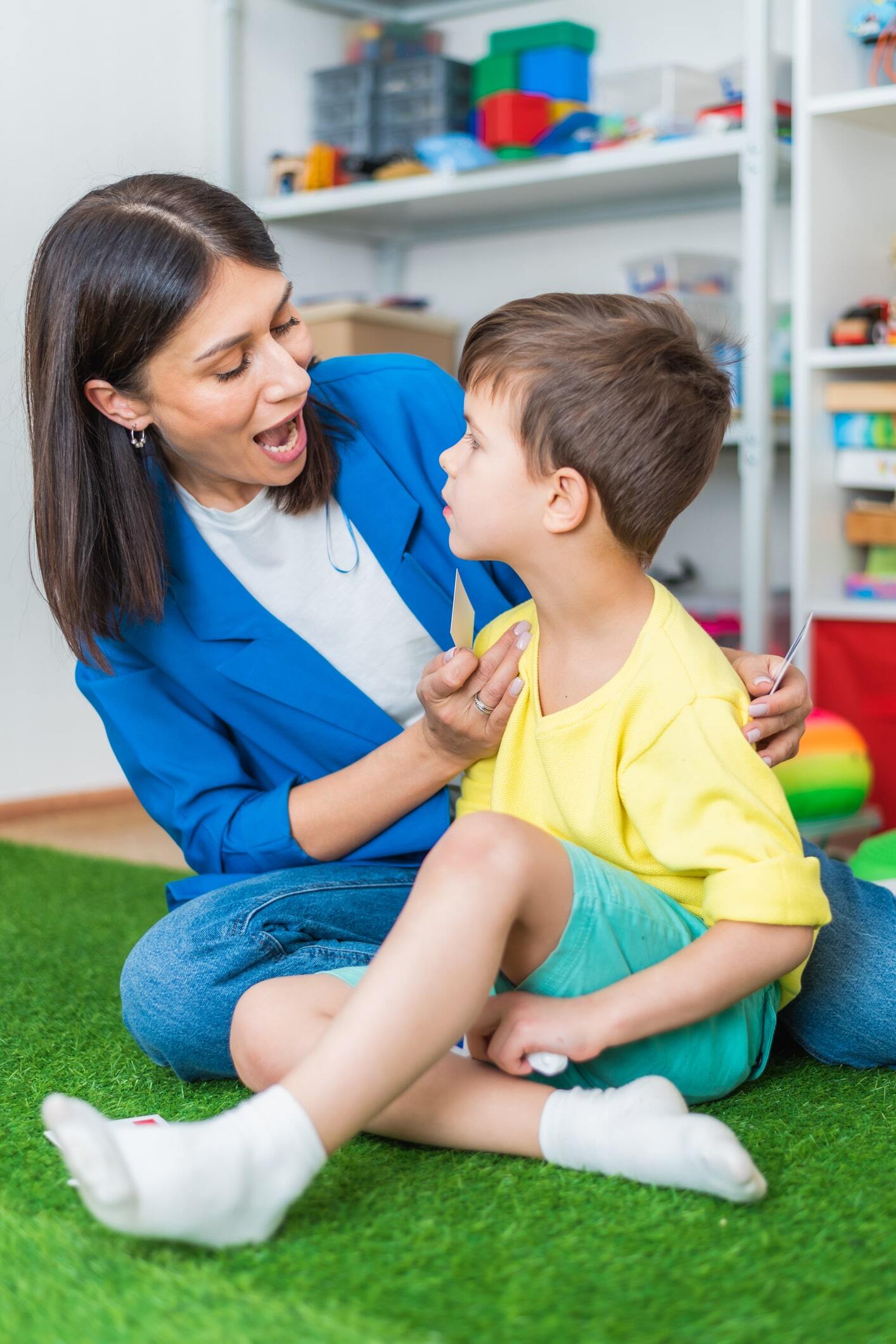 A woman speech therapist teaches a boy the correct pronunciation of words and sounds in an office