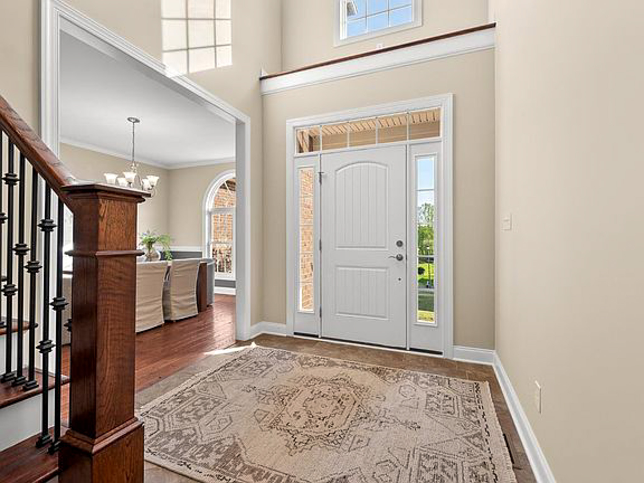 Bright foyer with a white front door, high ceilings, staircase with dark wood and iron railing, and a dining room visible to the left in the home of sponsored residential provider Lisa Reed in Lynchburg, Virginia.