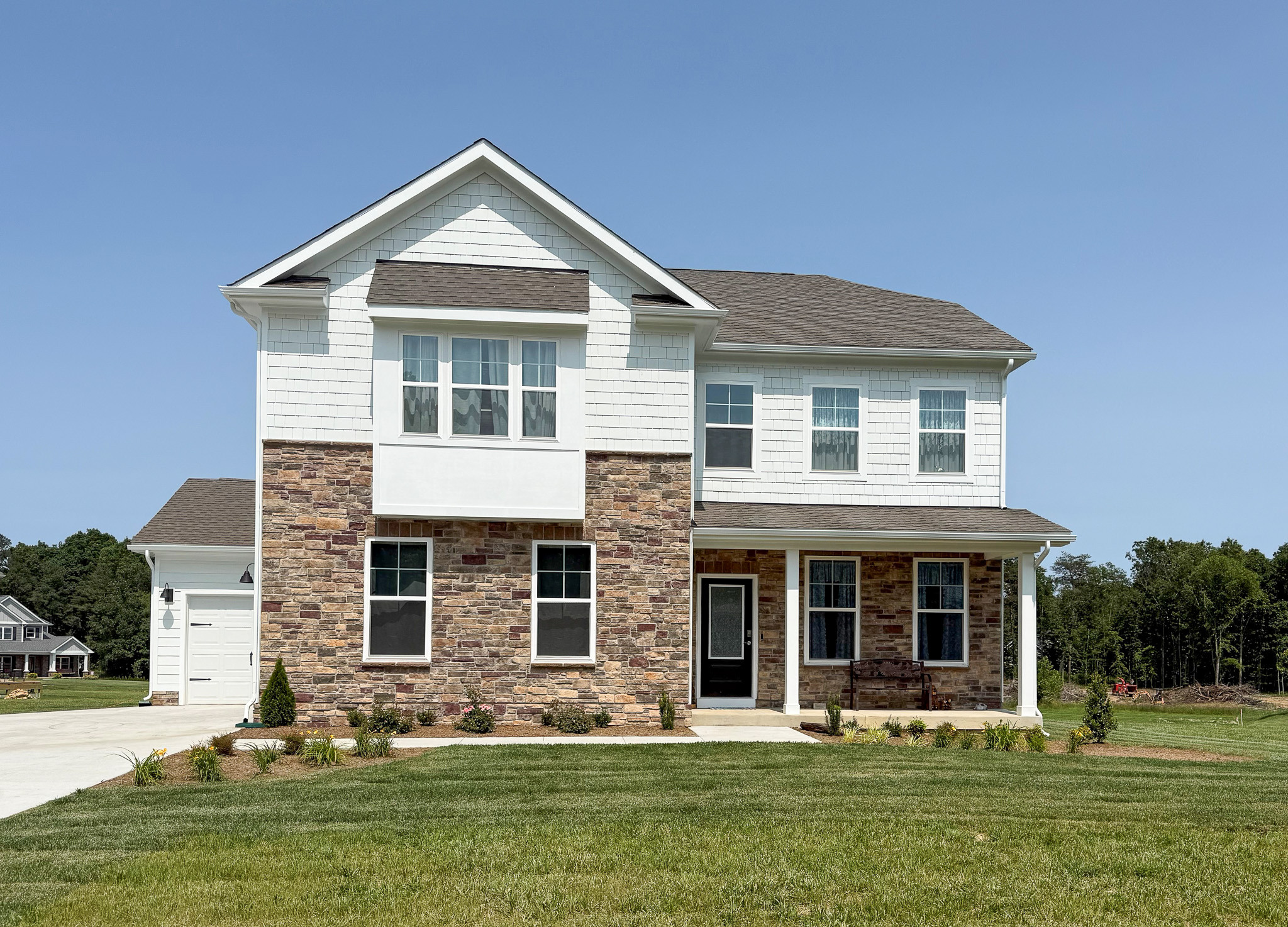 Two‑story white house with stone facade, front porch, attached garage, and a large grassy yard belonging to Group Home provider Traci Burch in Staurts Draft, VA.