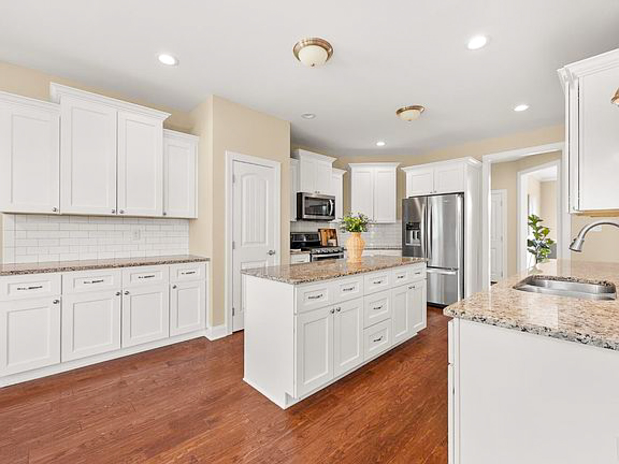 Bright kitchen with white cabinets, granite countertops, stainless‑steel appliances, and a center island in the home of sponsored residential provider Lisa Reed in Lynchburg, Virginia.