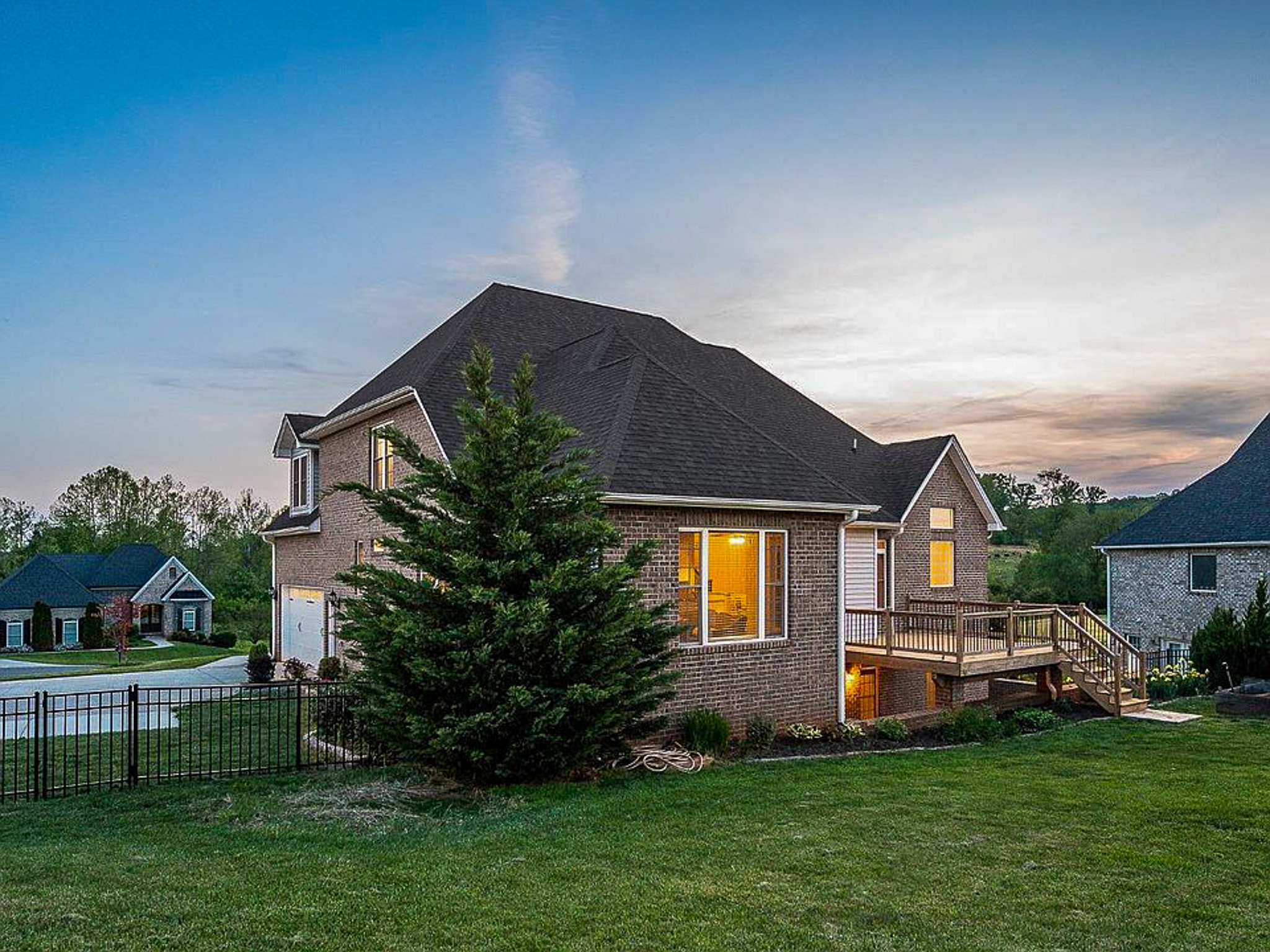 The backside of a single‑family brick home with large windows and a wooden ramp, set on a grassy lot at dusk, belonging to sponsored residential provider Lisa Reed in Lynchburg, Virginia.