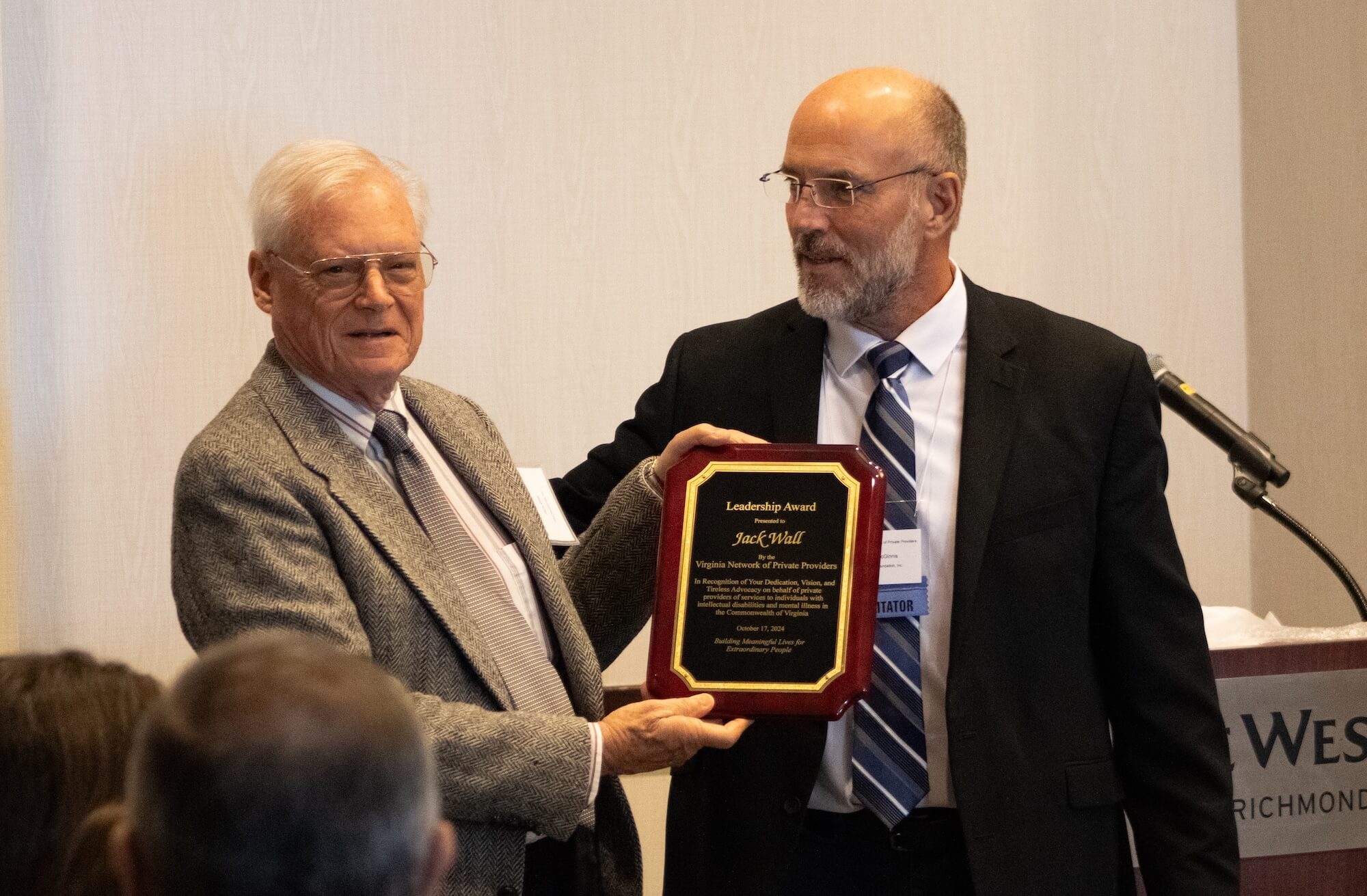 Wall’s founder Jack Wall wearing a suit receiving an award from a man in front of a microphone