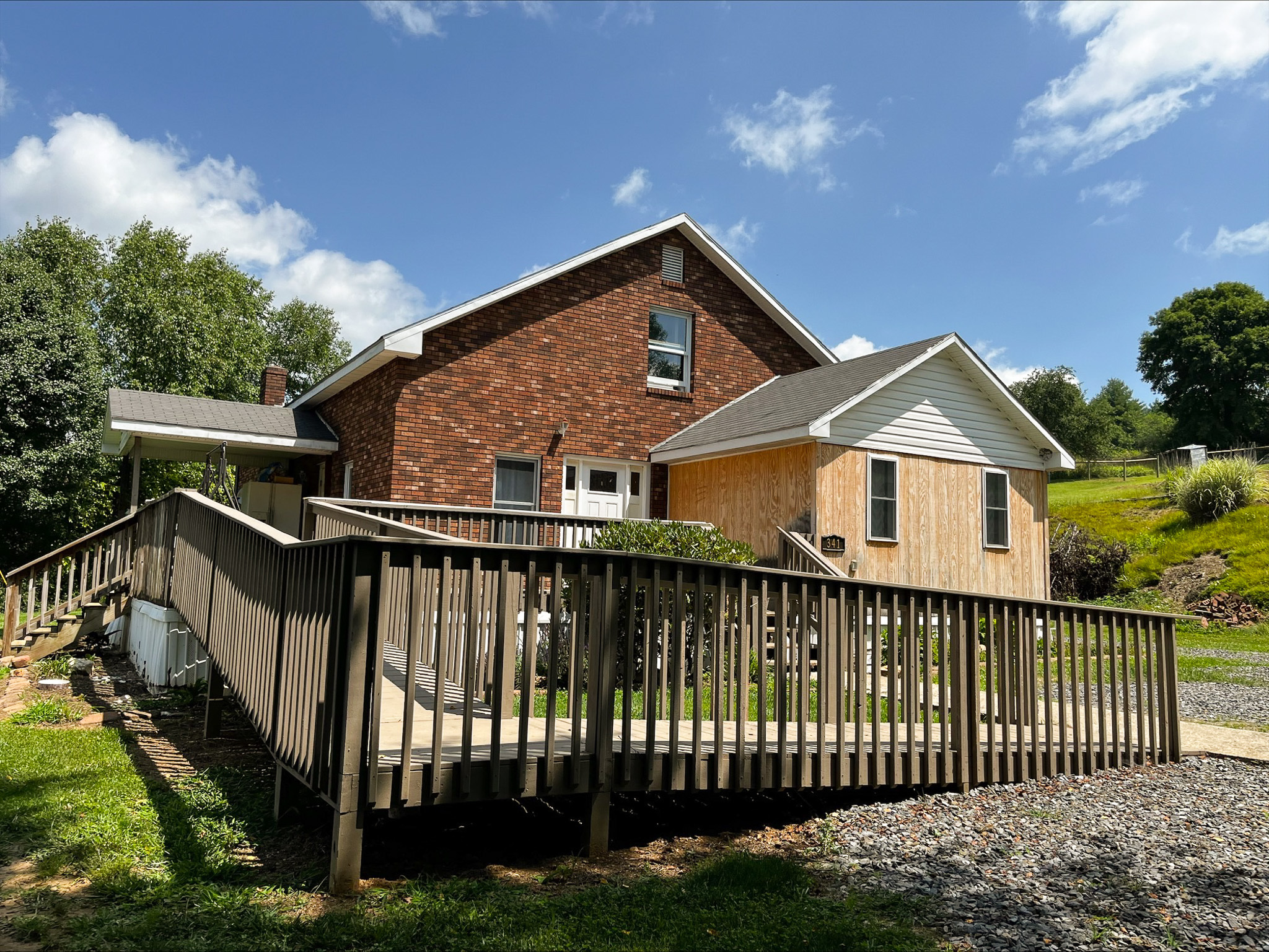 Brick and light‑wood house with a long wooden accessibility ramp and gravel driveway in foreground at the home of Sponsored Residential Provider Dara Short in Willis, Virginia.