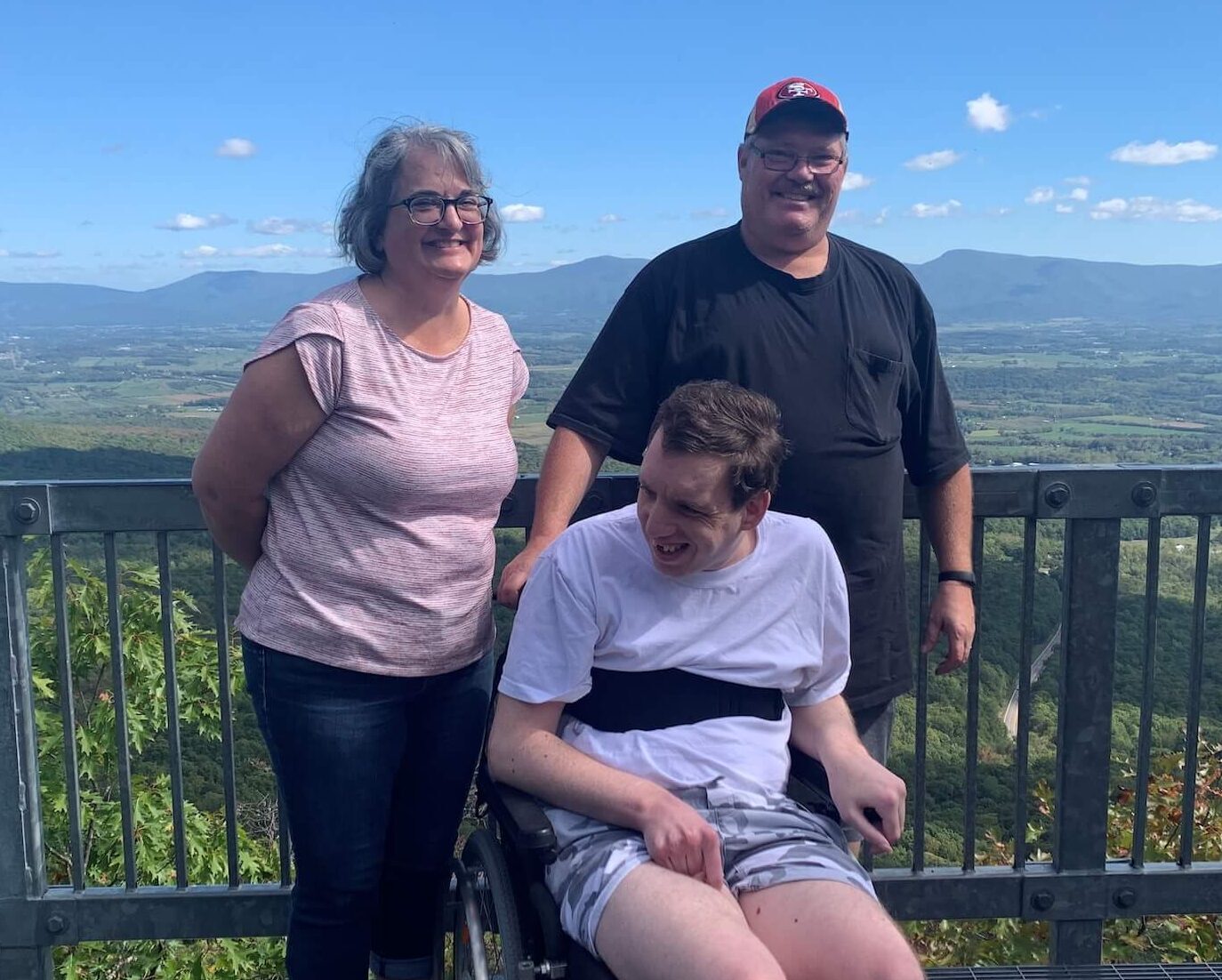 Two men and a woman at a scenic overlook smiling at the camera