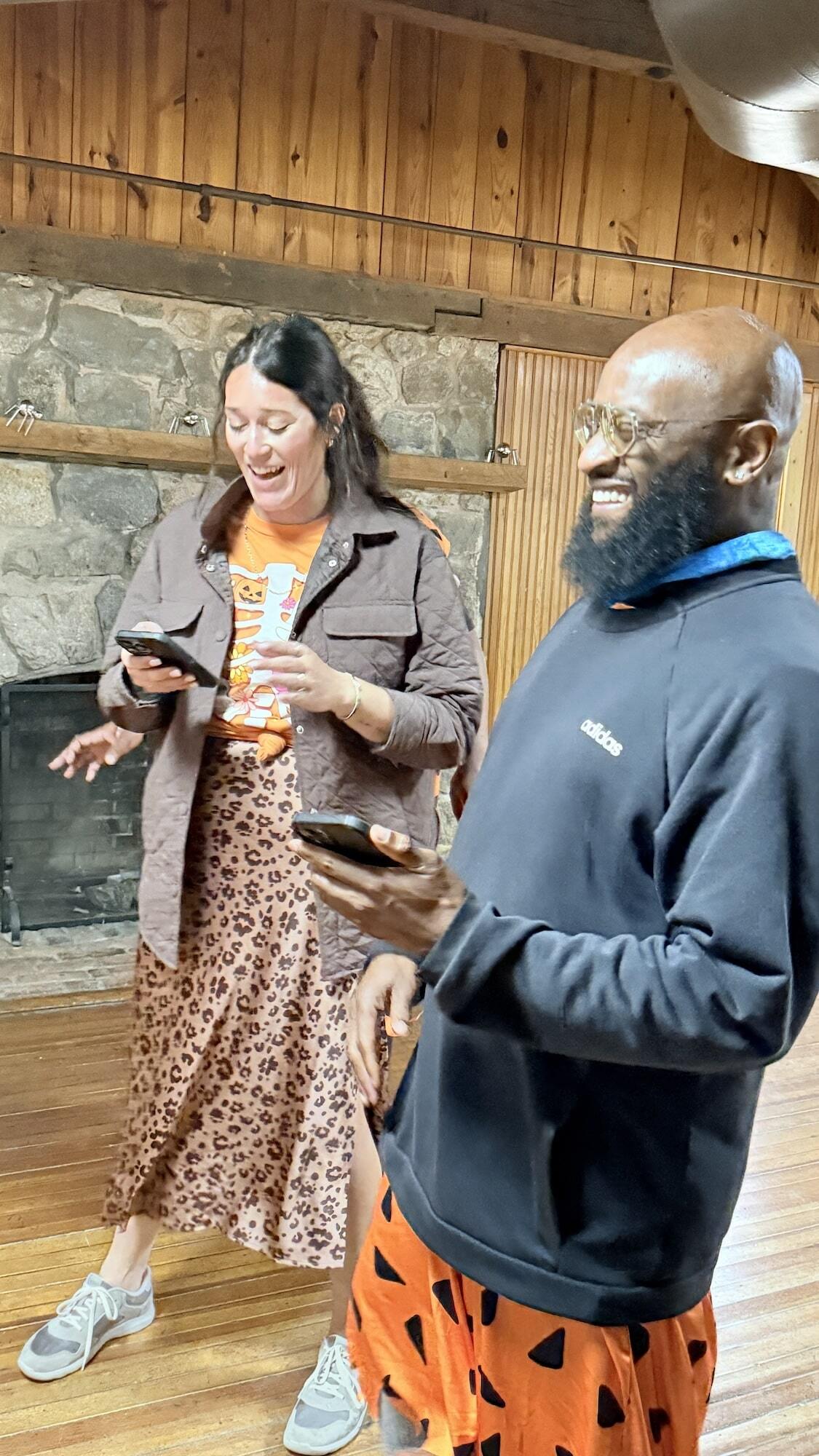 A man and woman exchanging laughter while looking at phones